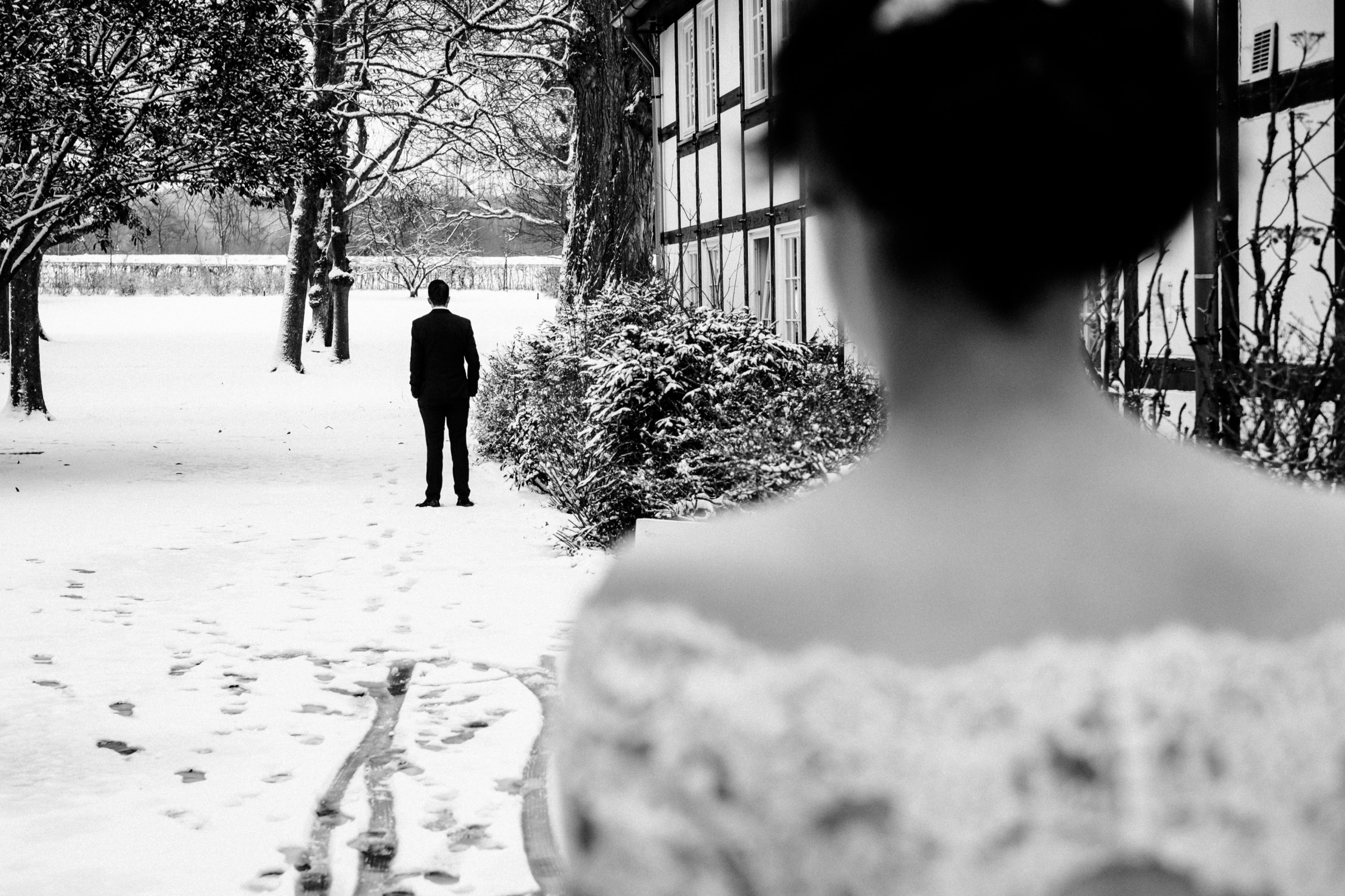 Winterhochzeit: Bräutigam steht mit Rücken zur Braut, Blick über die Schulter der Braut