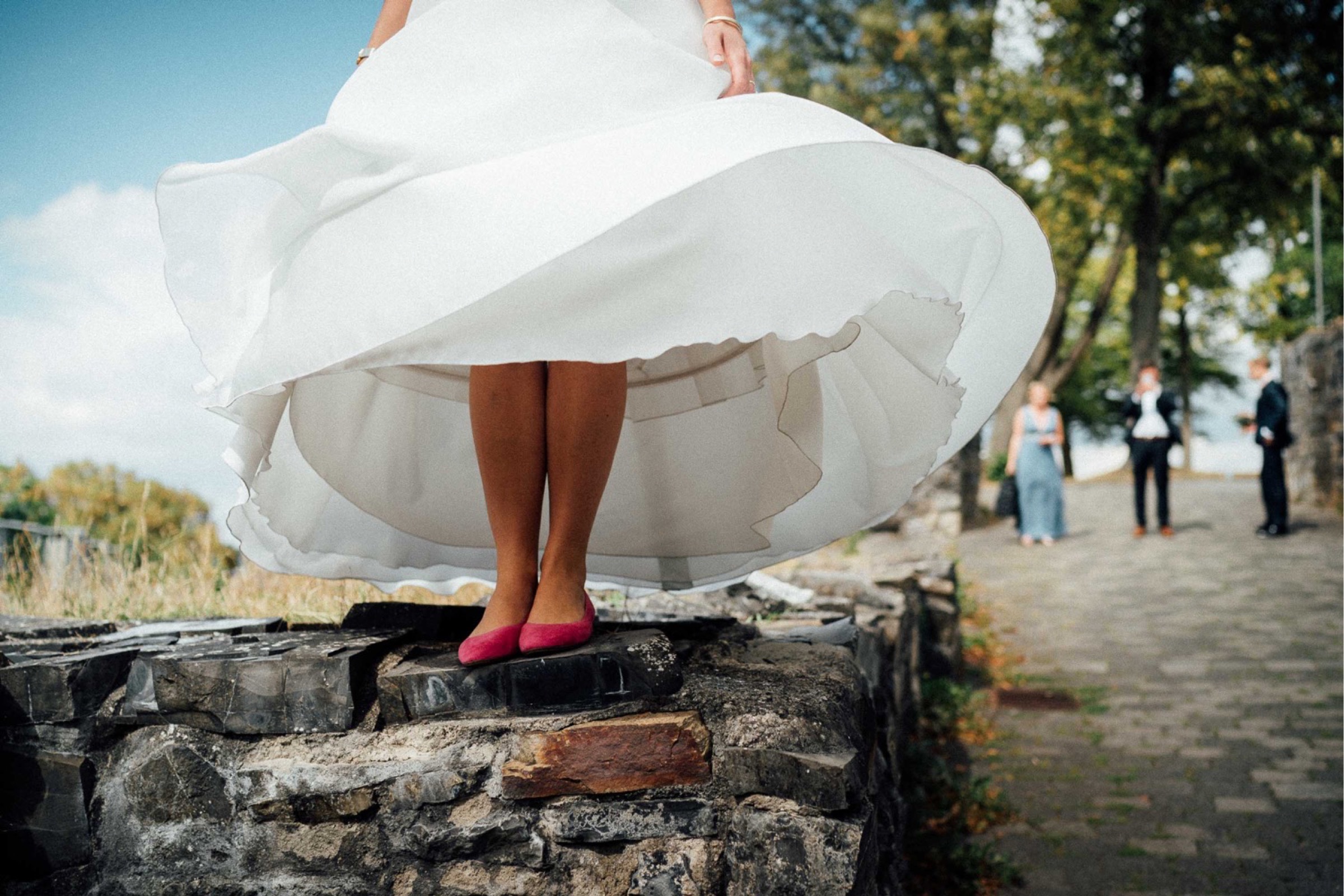 Herbsthochzeit: der Rock des Brautkleids weht hoch und man sieht die pinken Brautschuhe