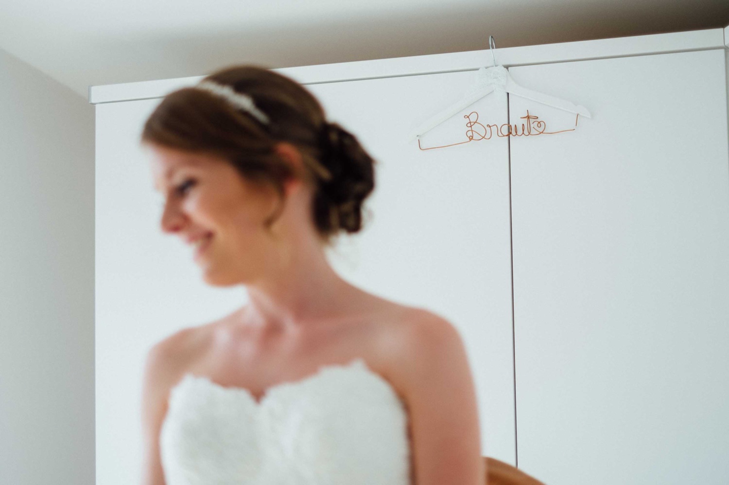 Hochzeit in Bremen: Braut im Vordergrund, im Hintergrund der Kleiderbügel mit dem aus Draht gebogenen Braut-Schriftzug
