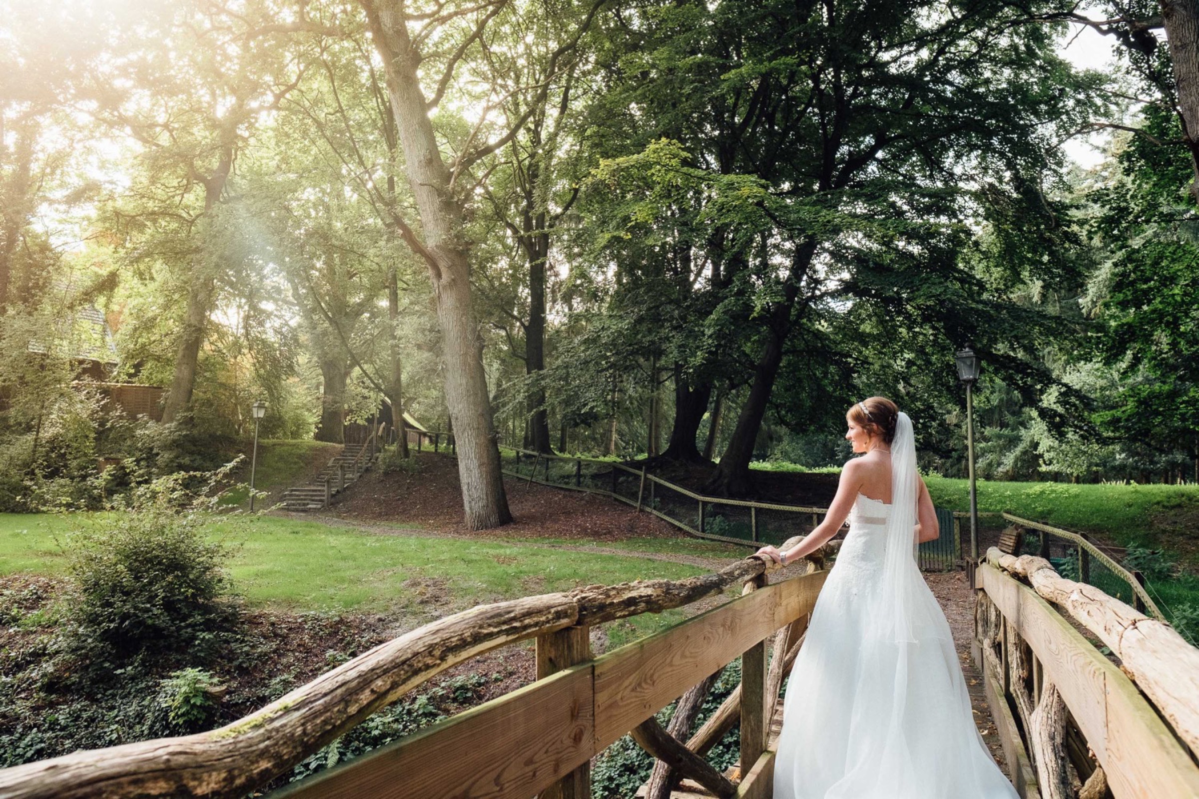 Hochzeit in Bremen: Braut auf einer Holzbrücke, im Hintergrund Wald