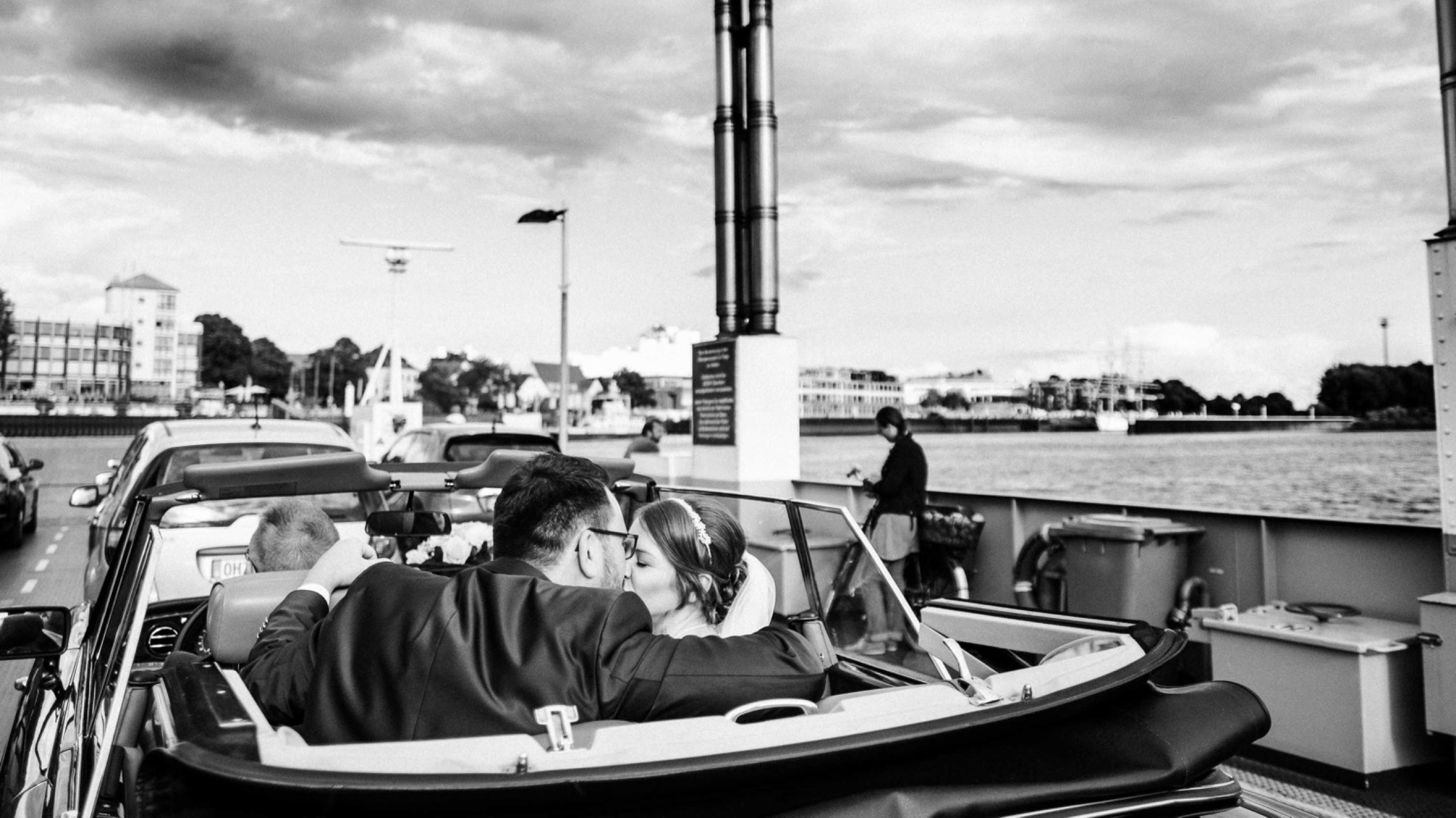 Hochzeit in Bremen: Rolls-Royce mit offenem Verdeck auf der Fähre, das Brautpaar küsst sich