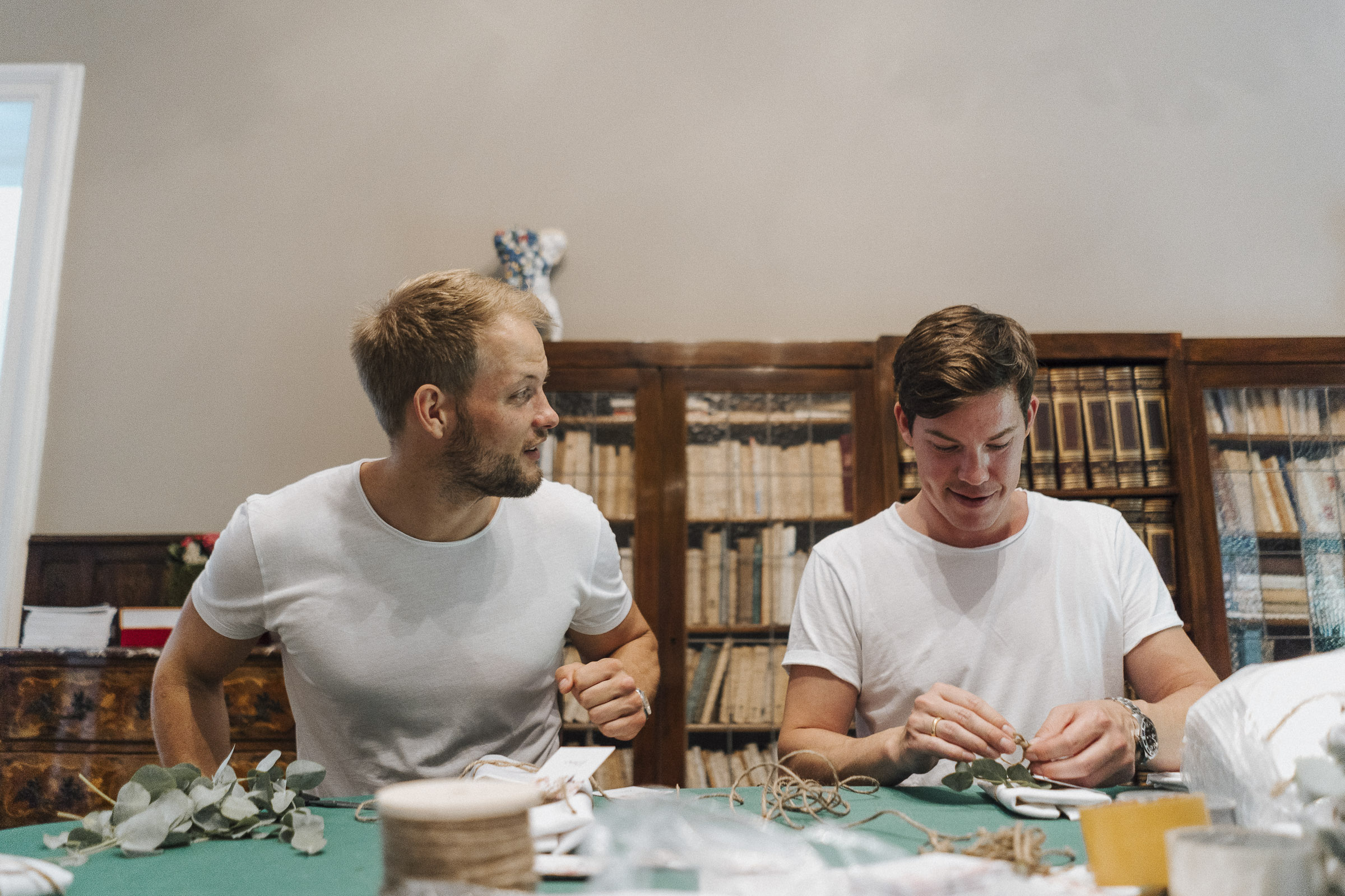 Hochzeit in Italien: zwei Männer basteln Tischdeko an einem Tisch