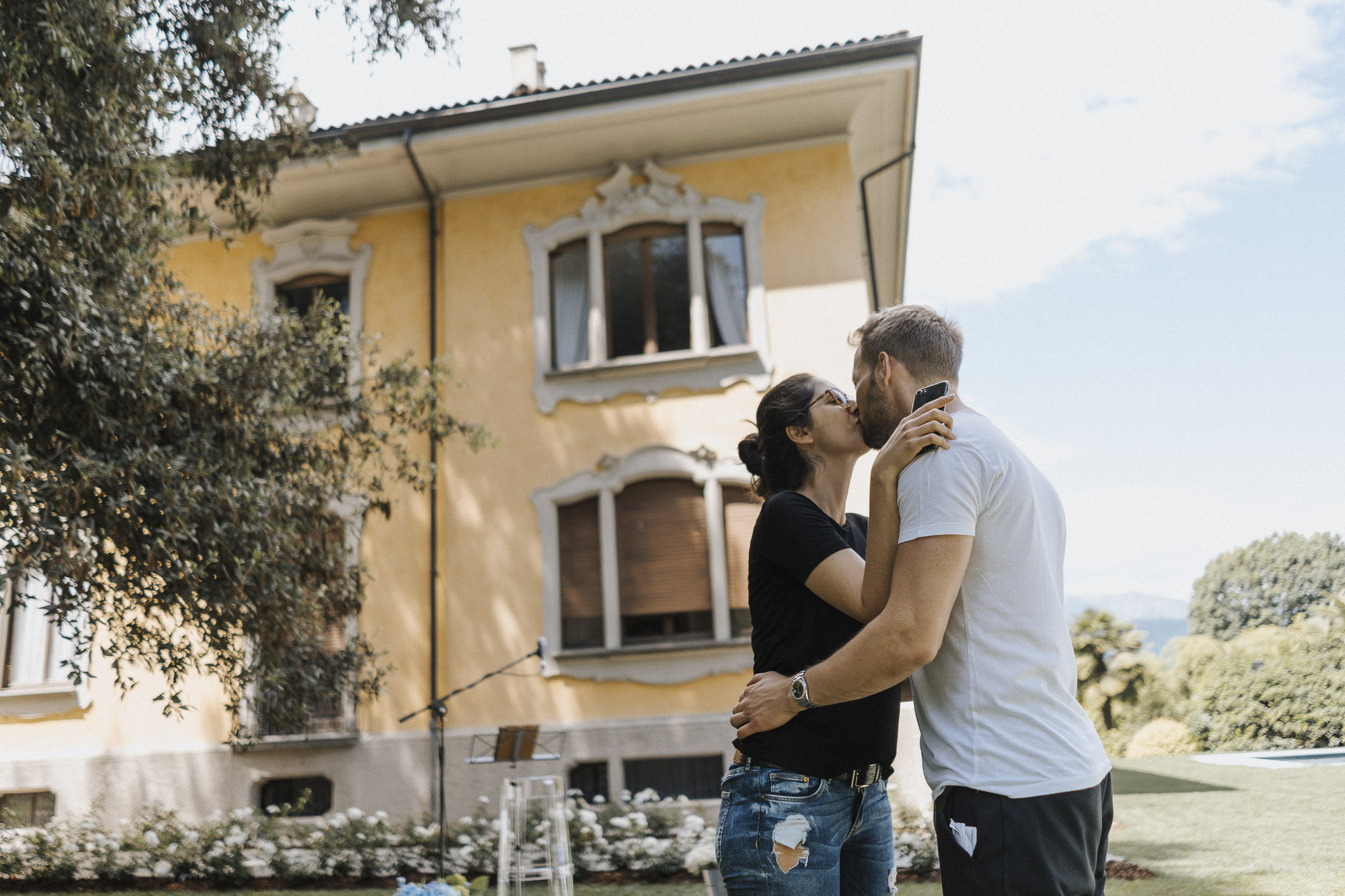 Hochzeit in Italien: Braut und Bräutigam küssend vor der Villa, beide noch nicht umgezogen für die Hochzeit