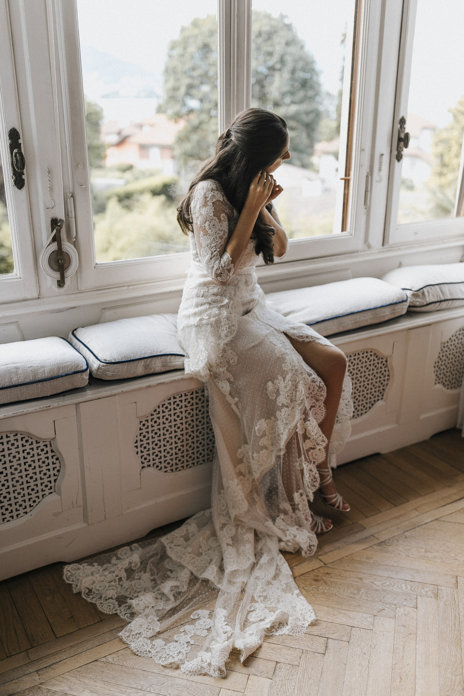 Hochzeit in Italien: Braut sitzt auf einer Fensterbank und legt sich die Ohrringe