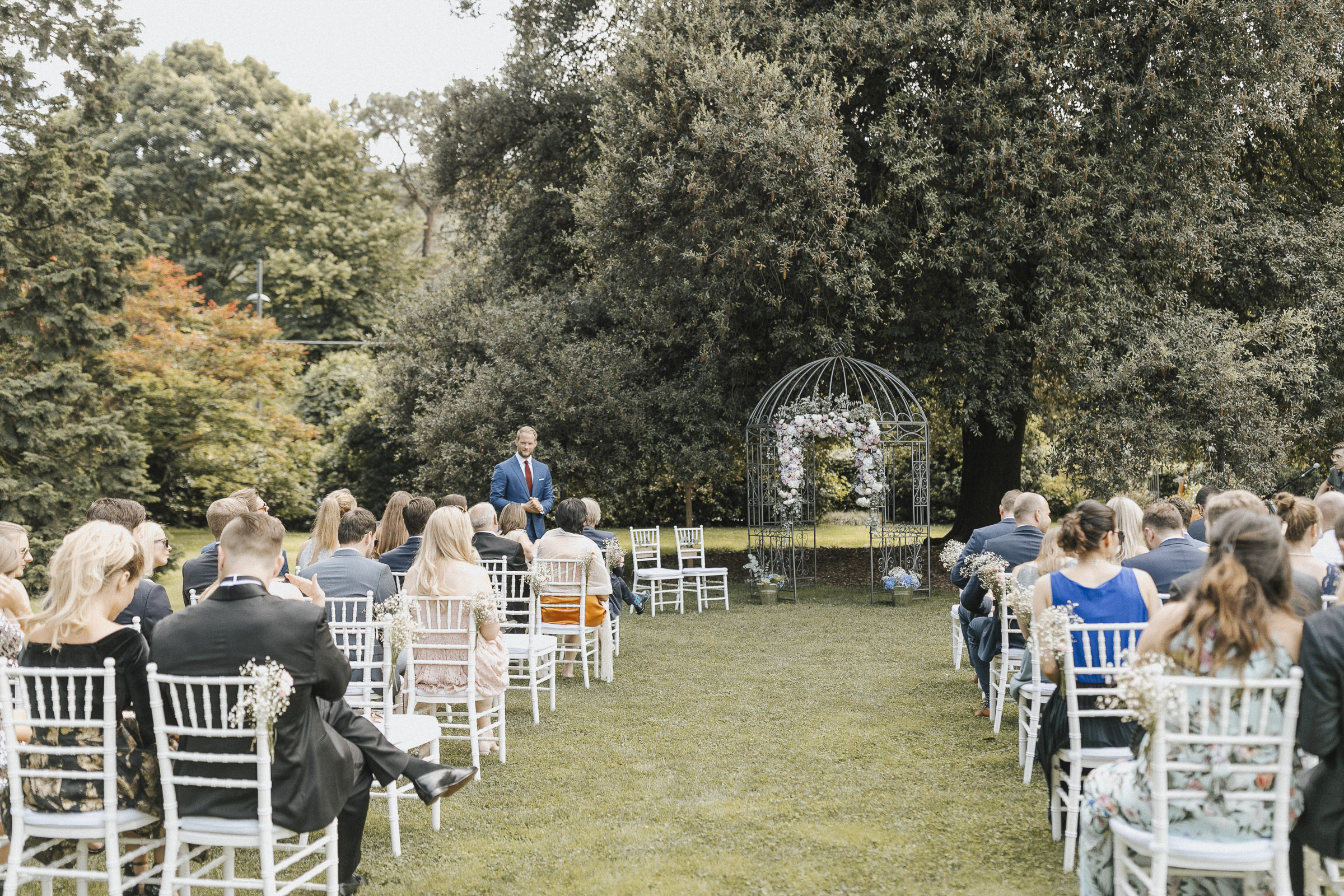 Hochzeit in Italien: Bräutigam und Hochzeitsgesellschaft warten im Garten auf die Ankunft der Braut