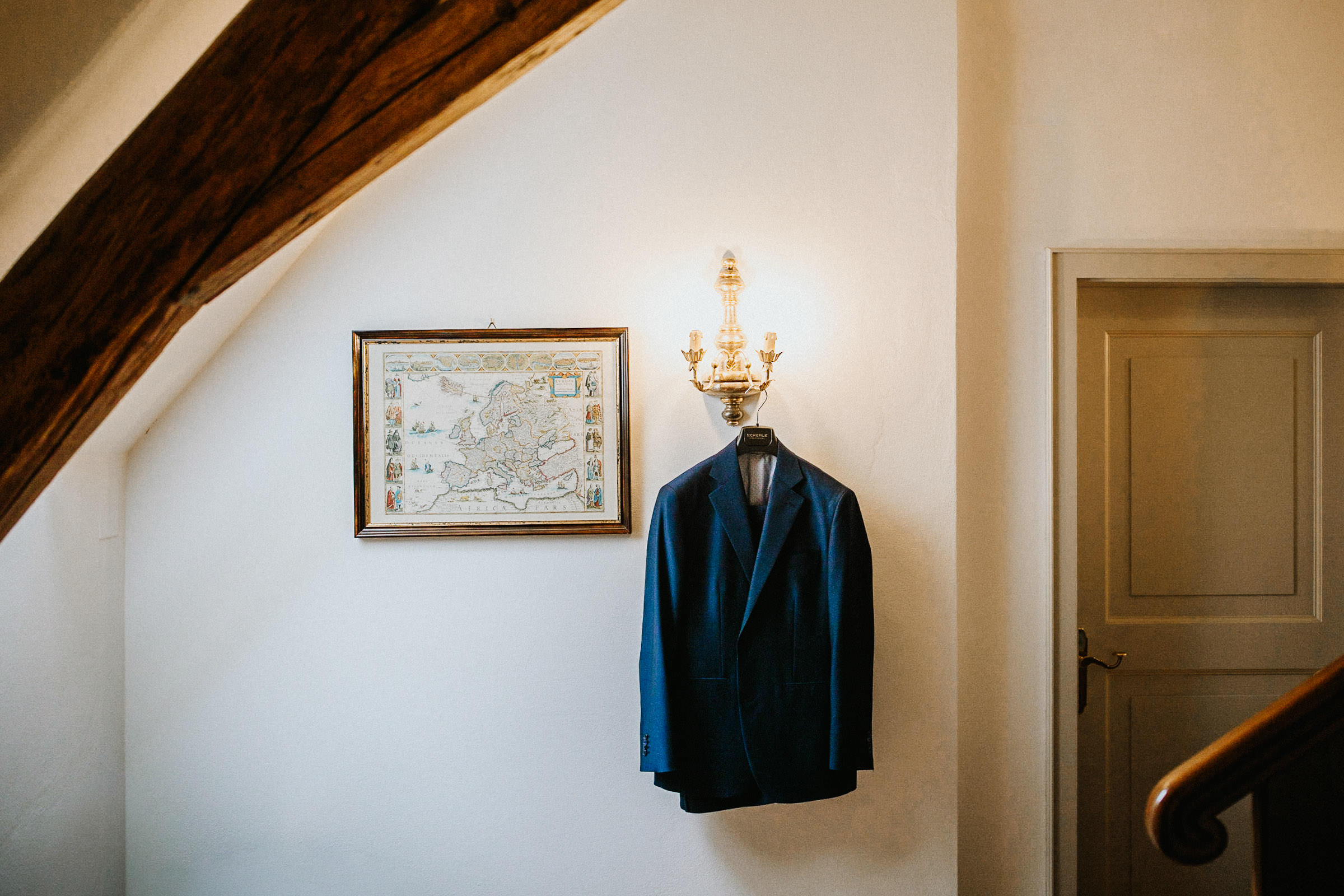 Schlosshochzeit: das Jacket des Bräutigams hängt an einem Leuchter im Hotelzimmer