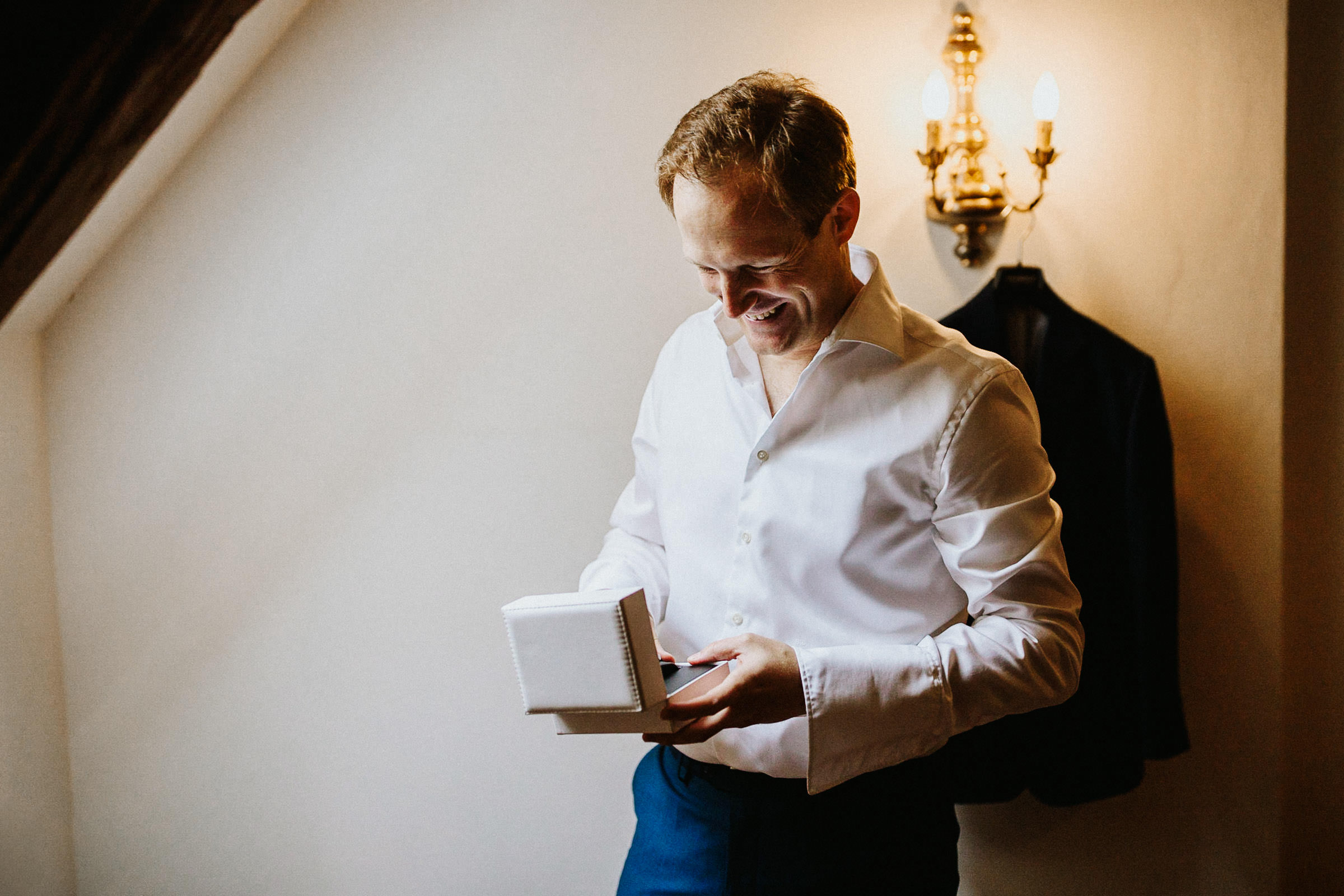 Schlosshochzeit: Bräutigam öffnet das Geschenk der Braut und freut sich