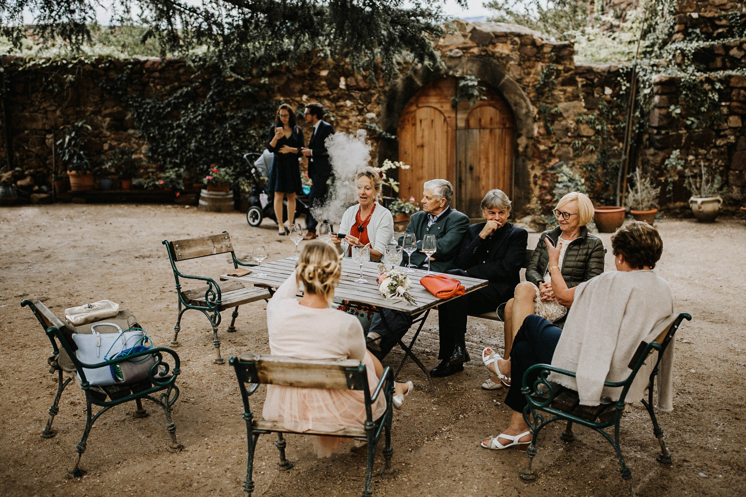 Schlosshochzeit: Hochzeitsgäste sitzen rauchend im Garten