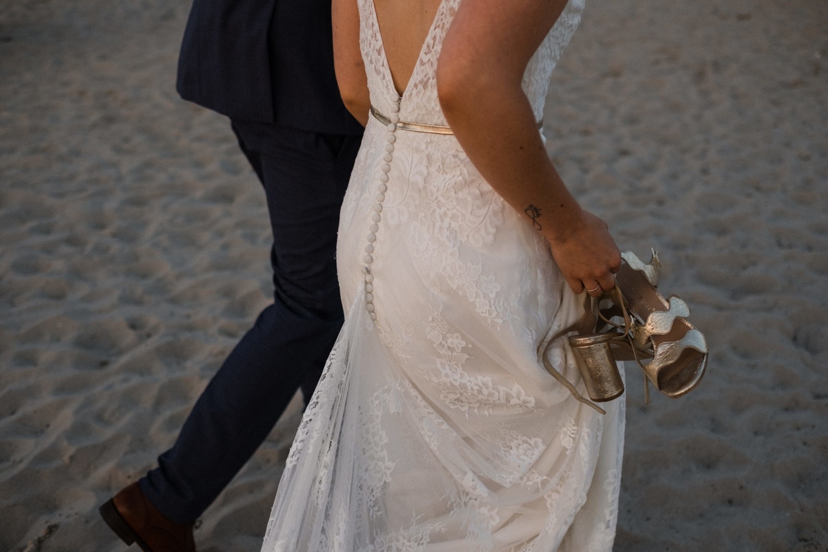 Strandhochzeit in Kiel: Brautpaar geht Hand in Hand den Strand entlang.