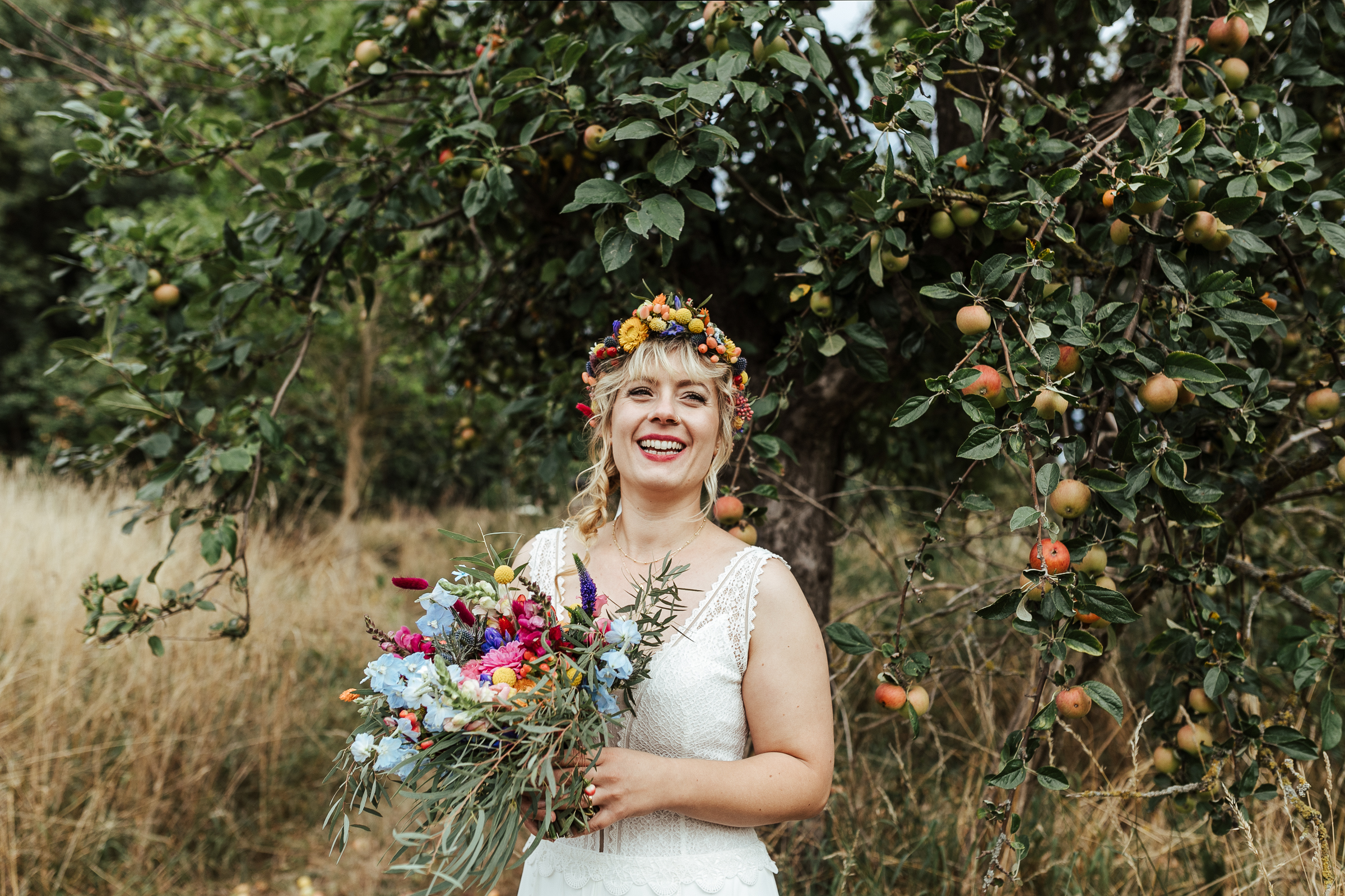 lachende Braut mit Blumenkranz im Haar und Brautstrauß