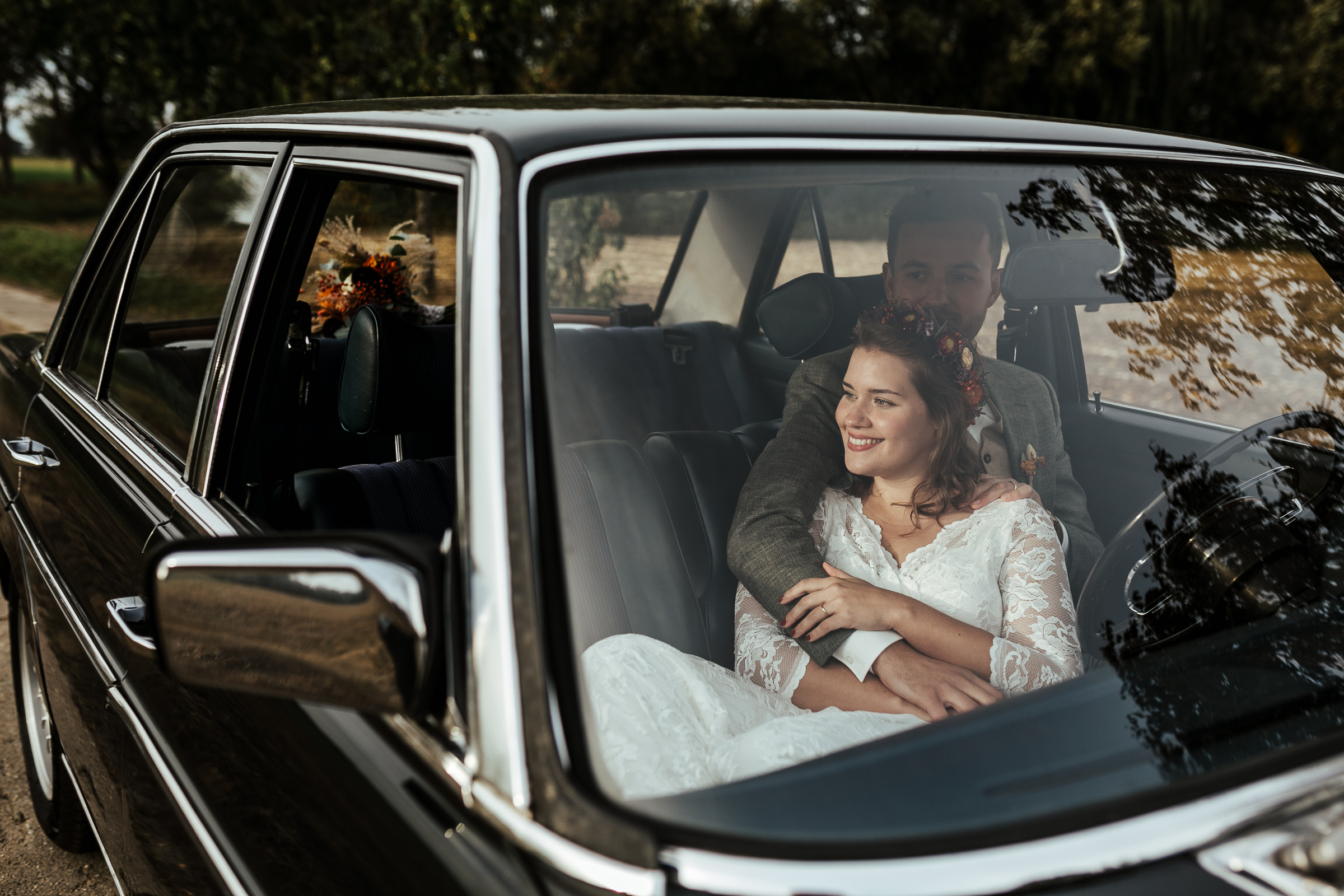 Blumenschmuck von Kopflegenden: Brautpaar im Auto
