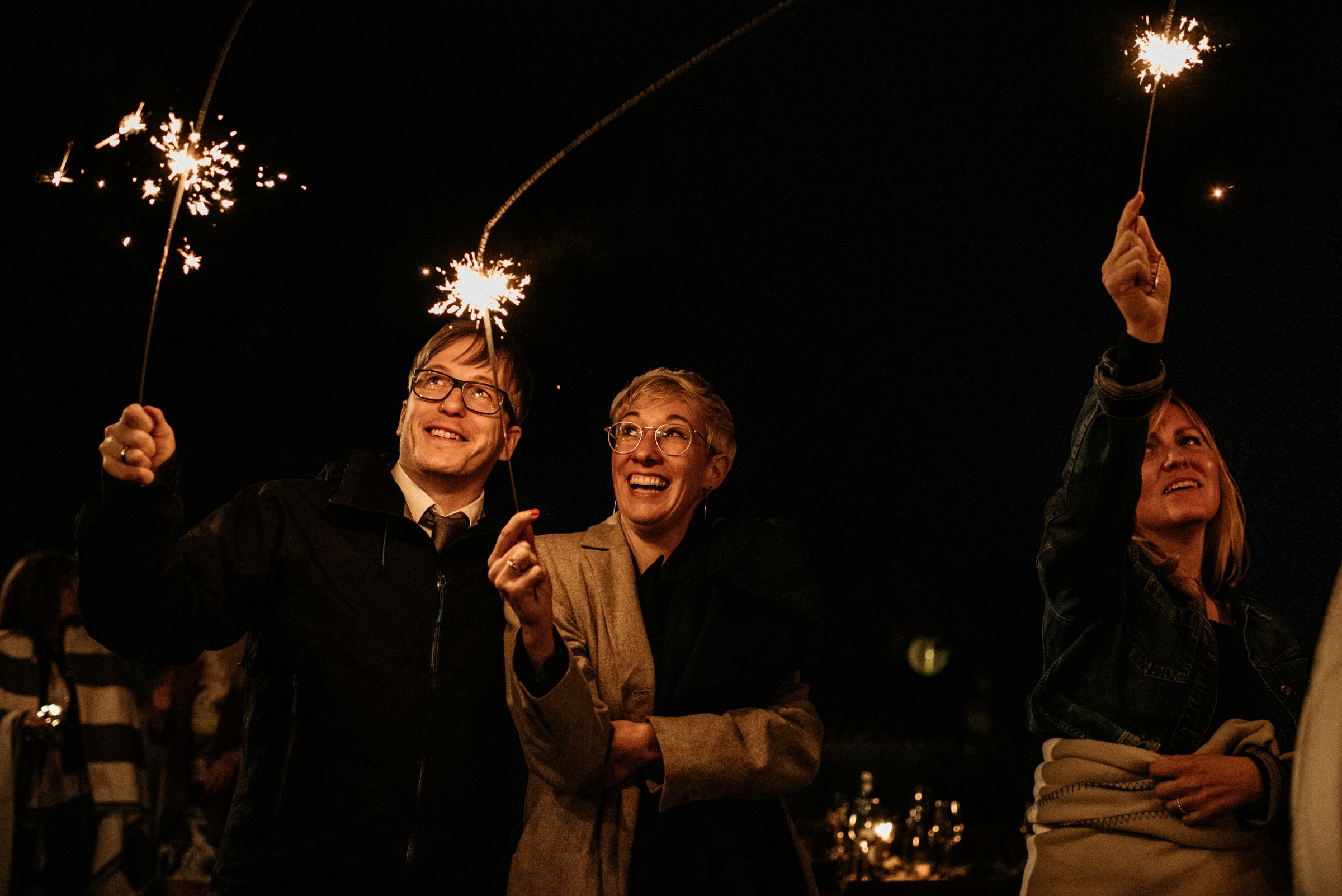 lachende Hochzeitsgäste mit Wunderkerzen