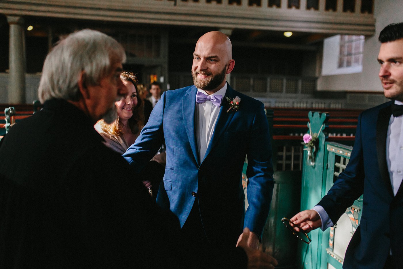 Urbane Hochzeit: Bräutigam in der Kirche mit den Hochzeitsgästen vor der Trauung