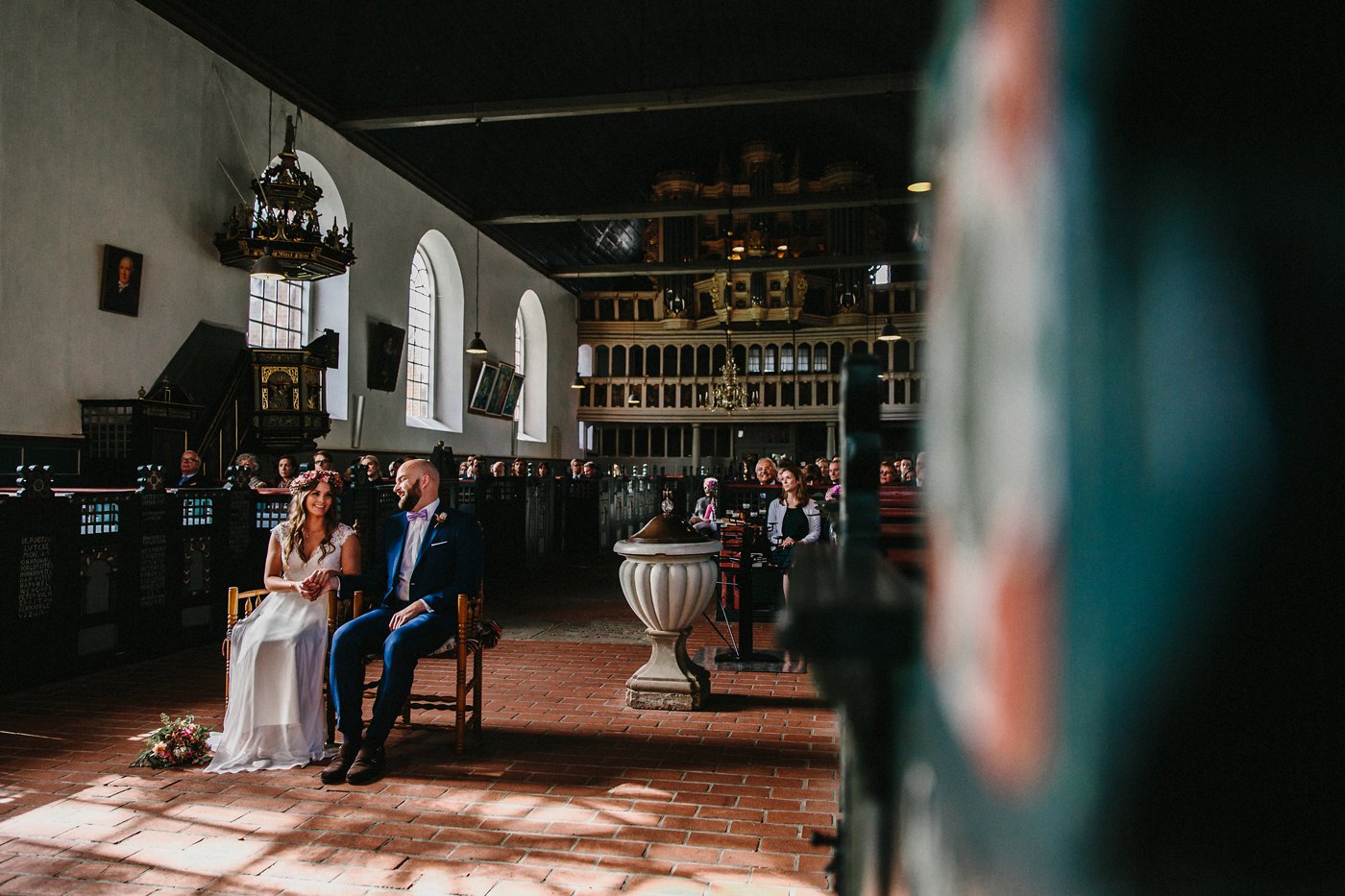 Urbane Hochzeit: Brautpaar sitzend vor dem Altar, durch die Kirchenfenster scheint die Sonne