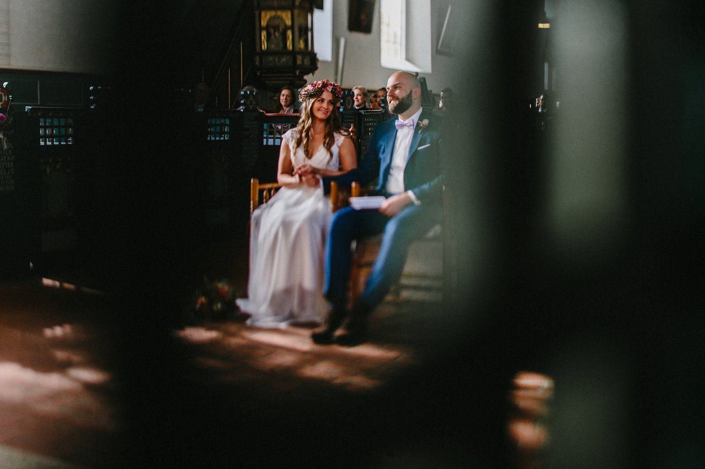 Urbane Hochzeit: Brautpaar sitzt vor dem Altar, Braut lächelt Bräutigam an