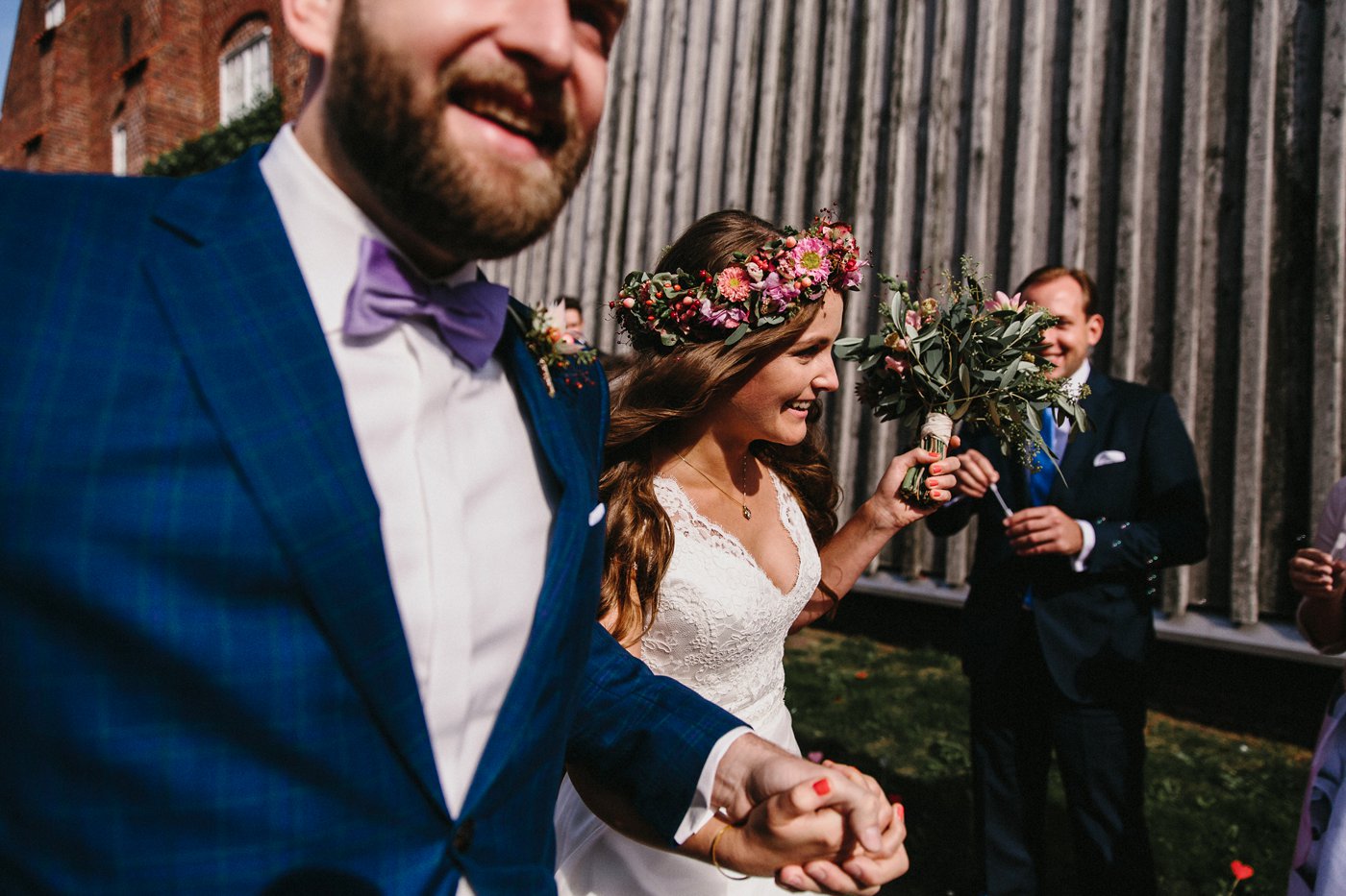 Urbane Hochzeit: Brautpaar läuft lachend durch das Spalier der Gäste