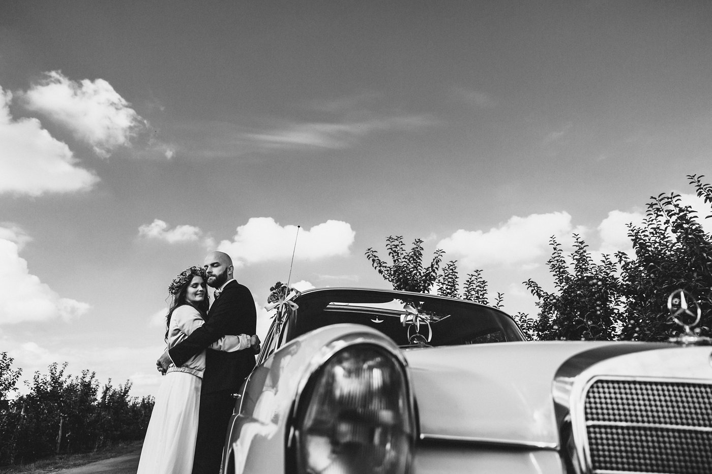 Urbane Hochzeit: Brautpaar eng umschlungen vor dem Hochzeitsauto