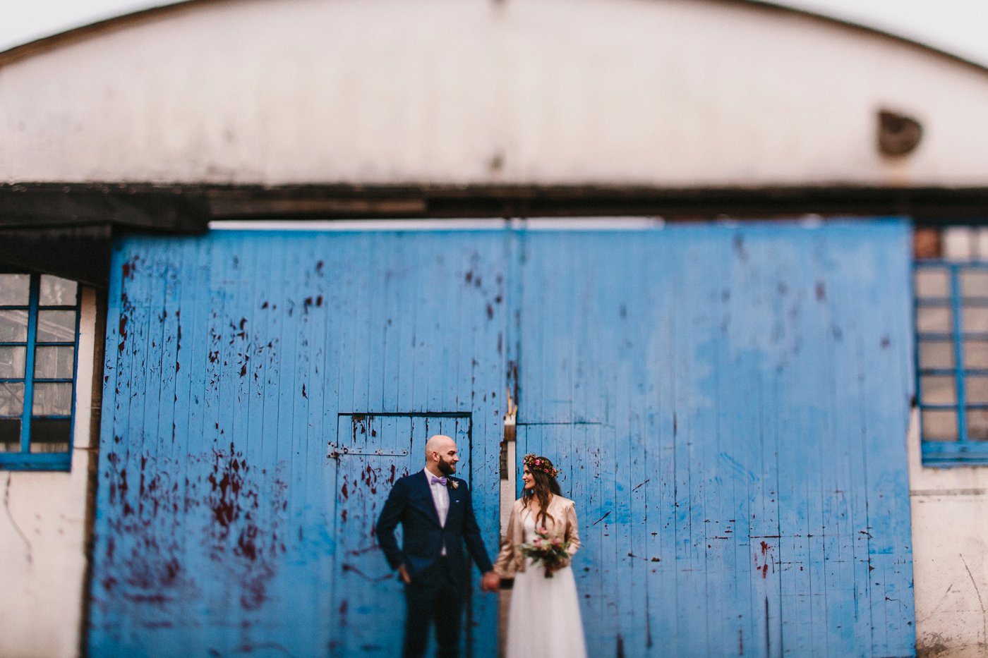 Urbane Hochzeit: Brautpaar Hand in Hand vor einer blauen Tür