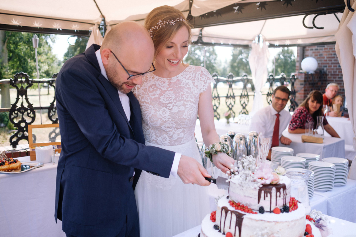Vintage-Hochzeit: Brautpaar schneidet die Hochzeitstorte an