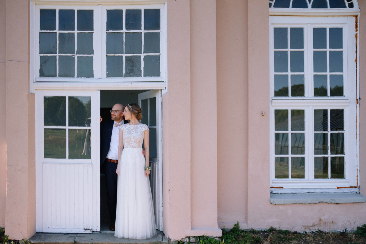 Vintage-Hochzeit: Brautpaar steht in der Terrassentür
