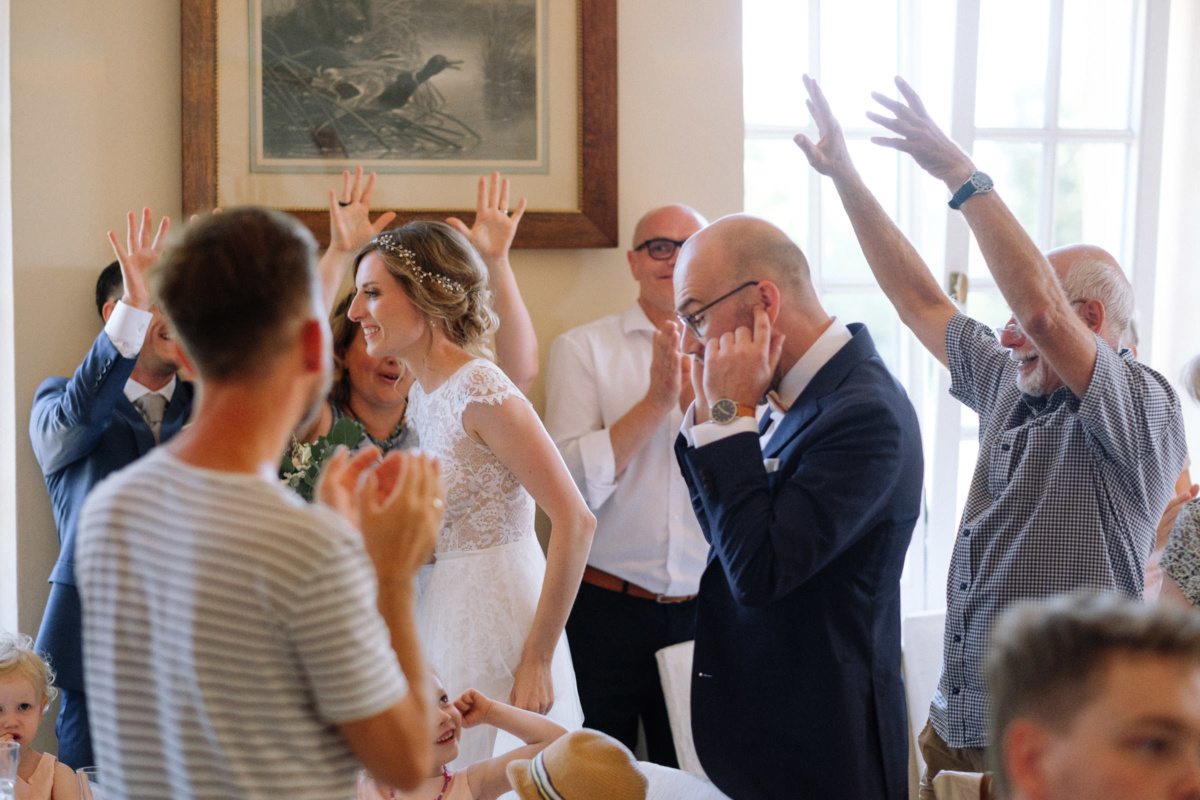 Vintage-Hochzeit: Hochzeitsgäste jubeln, Bräutigam hält sich die Augen zu