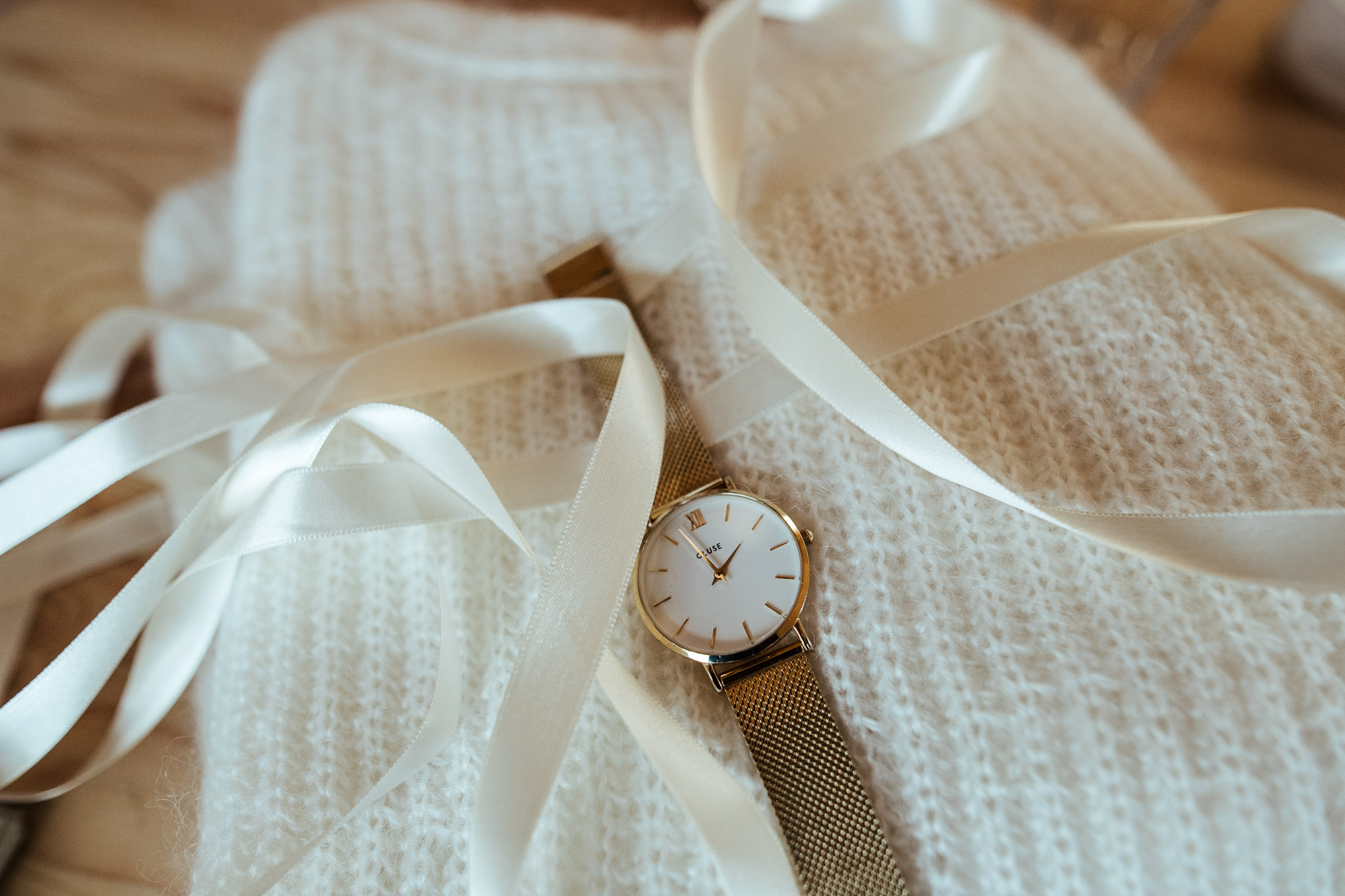 Landhochzeit: eine goldene Uhr liegt auf einem weißen Wollschal