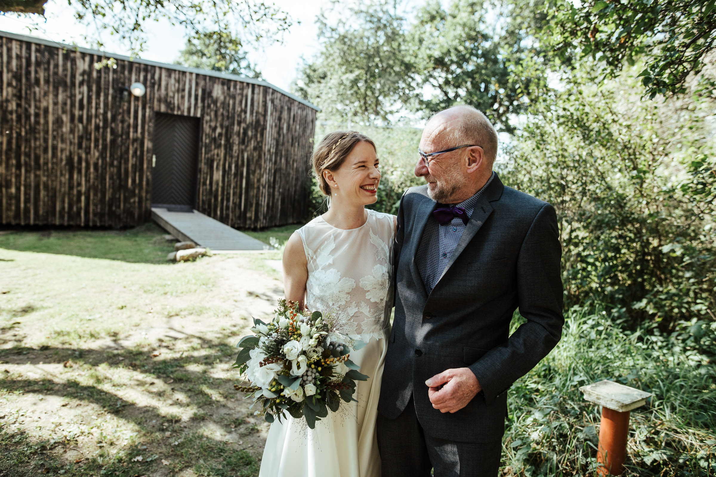 Landhochzeit: Braut Arm in Arm mit Brautvater auf dem Weg zur Trauung