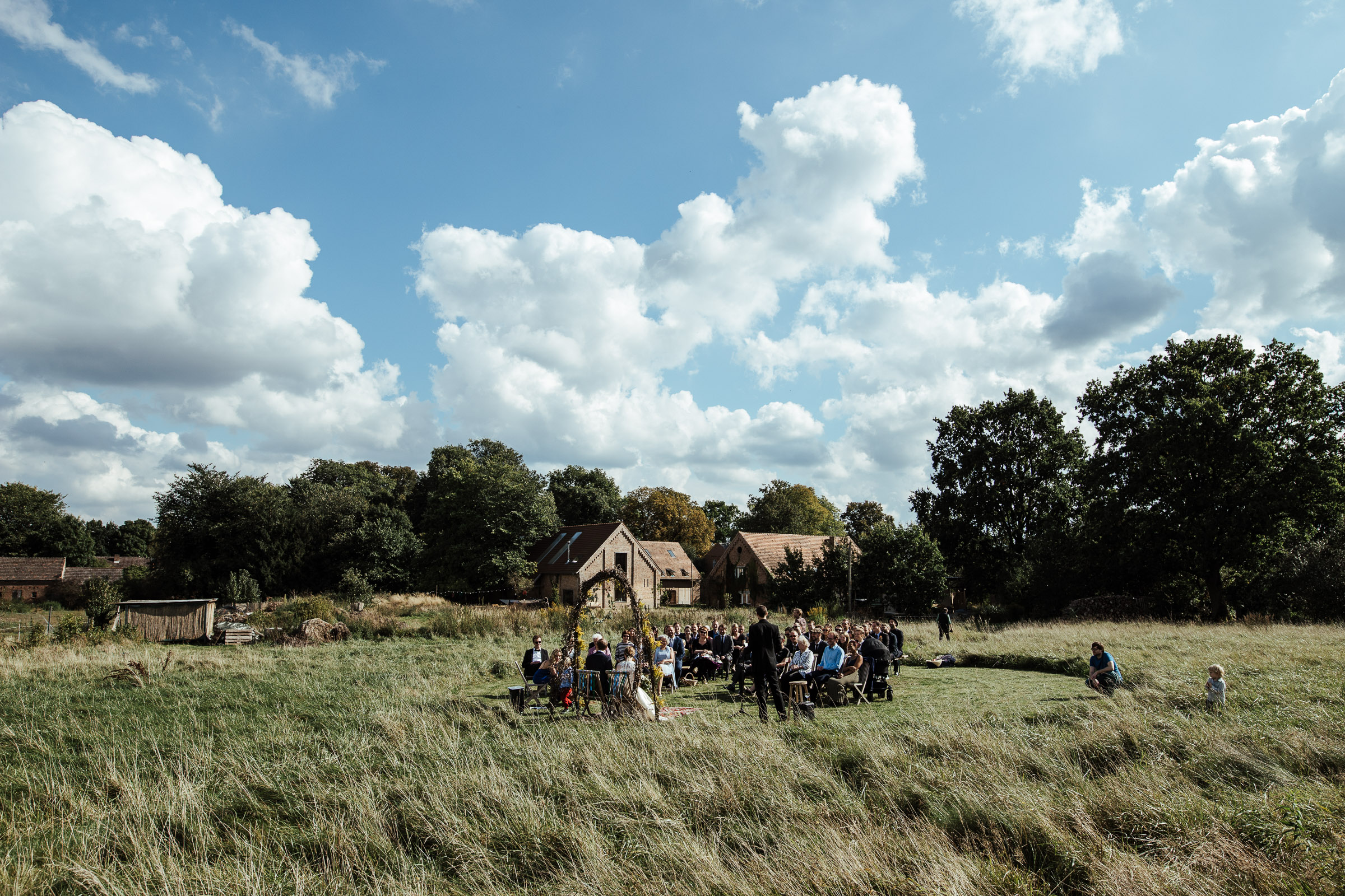 Landhochzeit: Blick auf die Wiese und die Hochzeitsgesellschaft