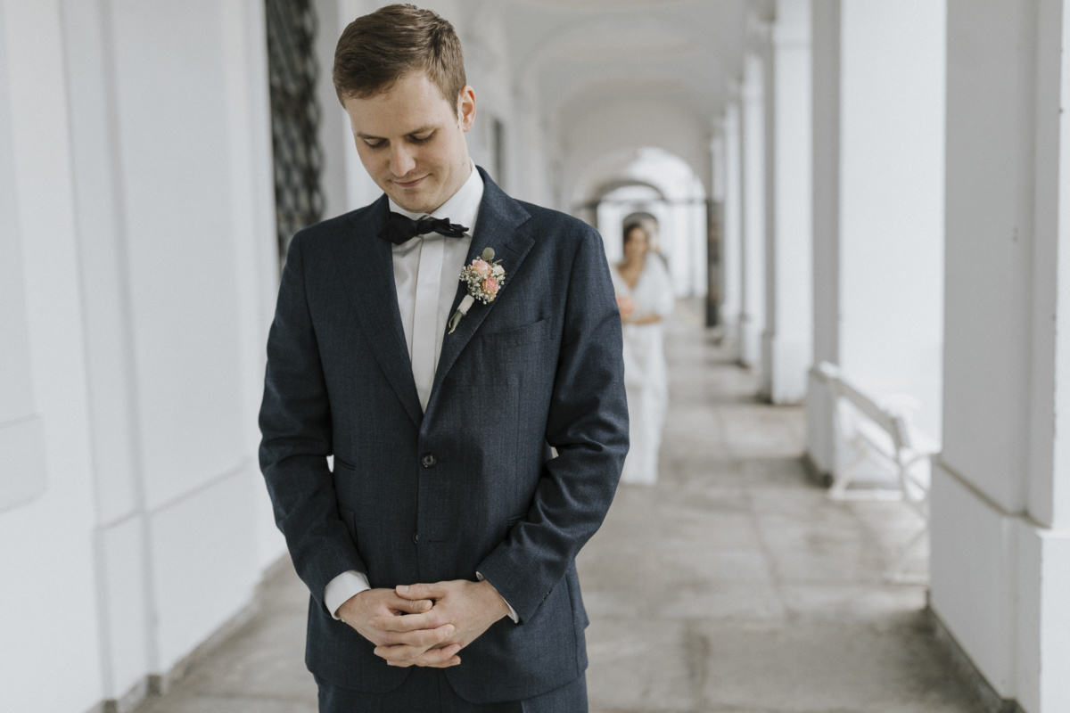 Hochzeitsfotograf in Augsburg: Bräutigam wartet auf First Look, hinter ihm steht seine Braut