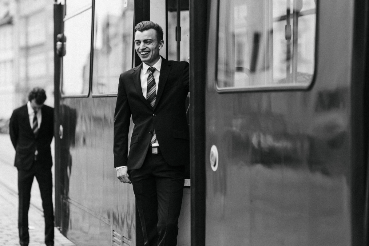 Hochzeitsfotograf in Augsburg: Hochzeitsgast steht am Ausgang der fahrenden Retro-Straßenbahn