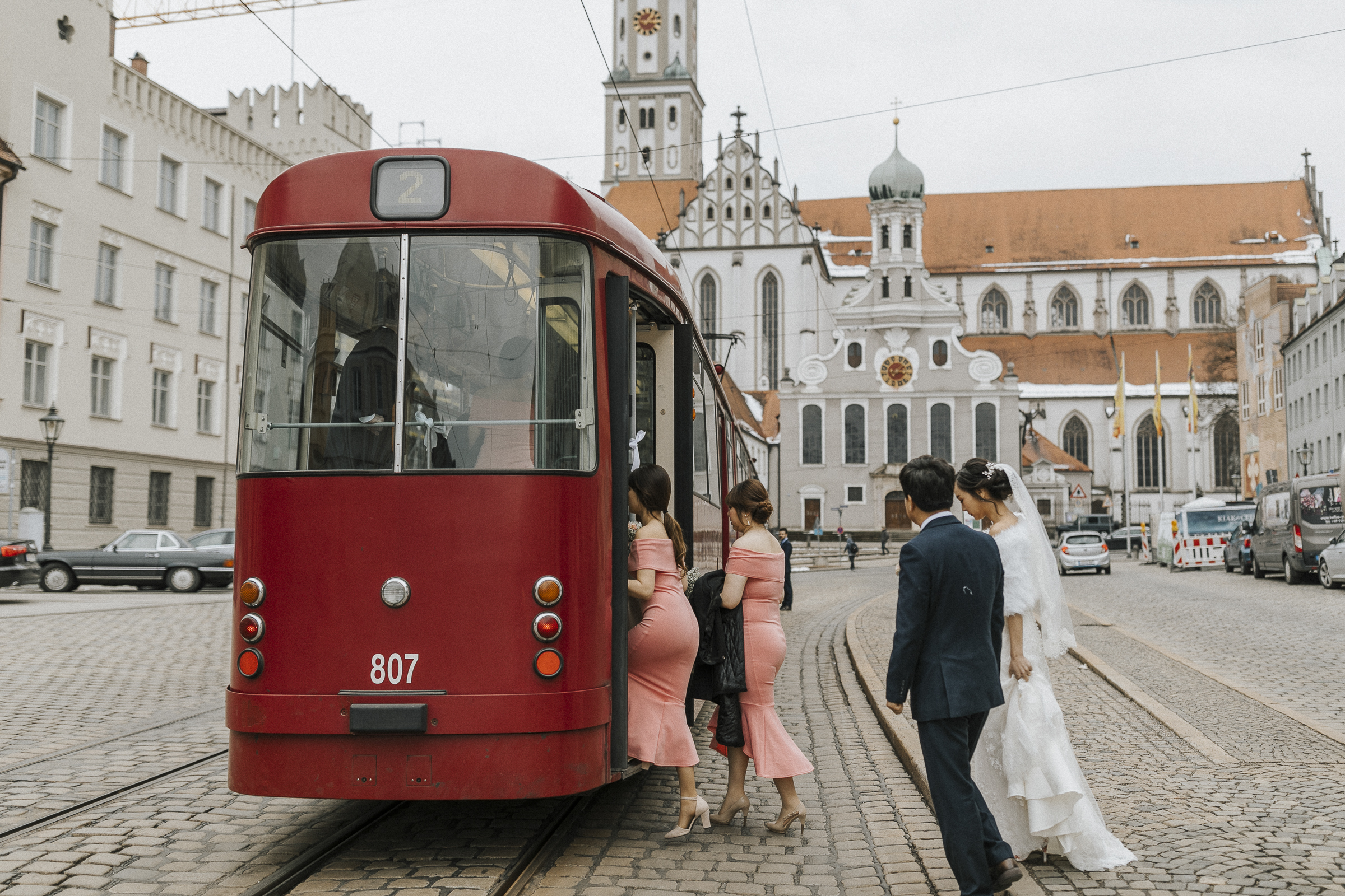 Hochzeitsfotograf in Augsburg: Trauzeuginnen und Brautpaar steigen in die Straßenbahn